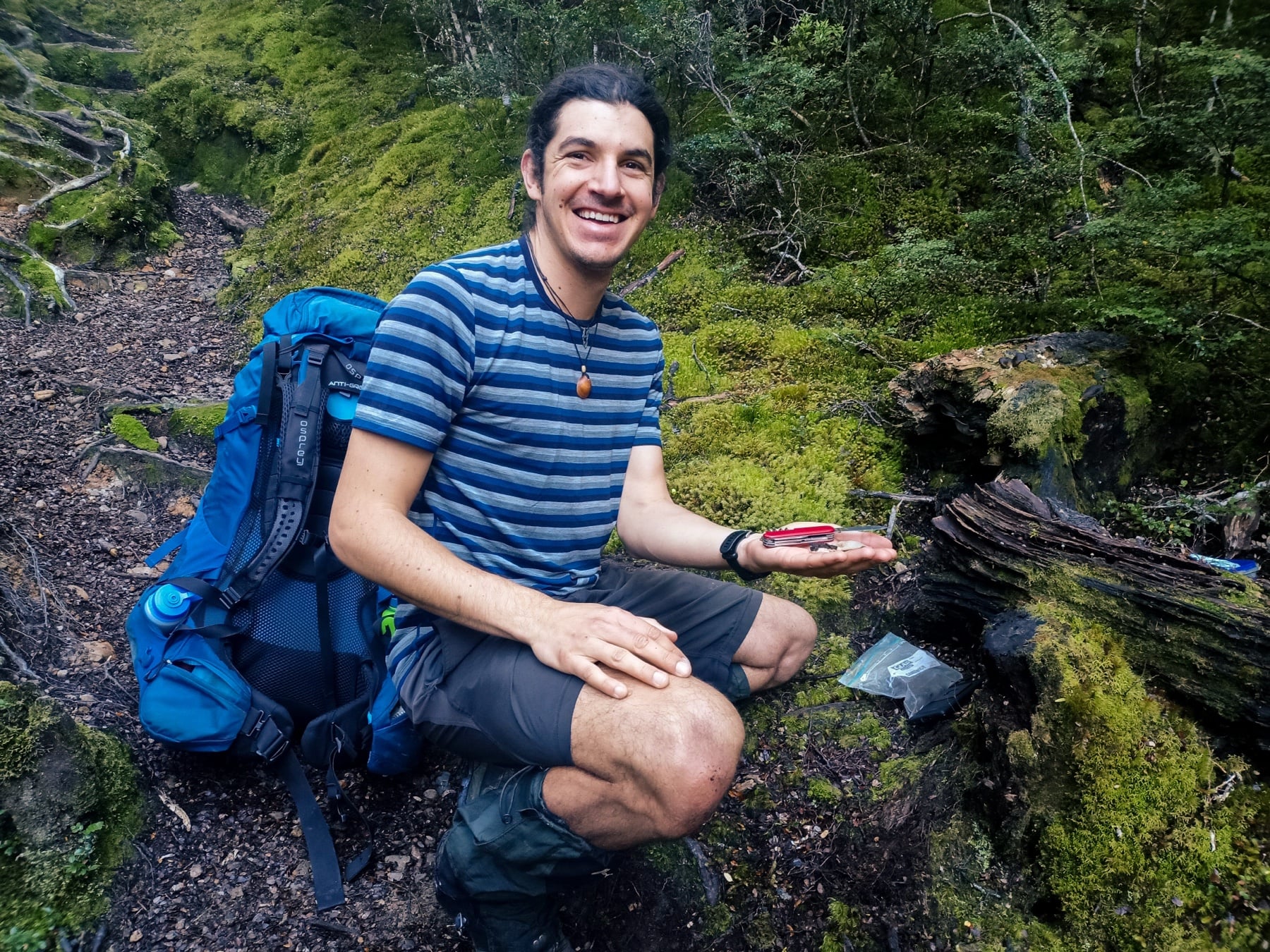 David sitting in native bush during a fungal foray, holding a freshly collected oyster mushroom.